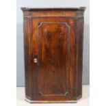 A George III mahogany hanging corner cupboard with dentil moulded cornice and fluted canted corners,