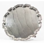 An Elizabeth II silver circular salver of Georgian design with moulded pie crust rim, on three
