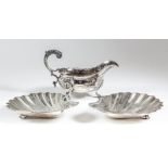 A George III silver oval sauce boat with shaped rim, leaf capped double C-scroll flying handle, on