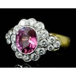 A modern 18ct gold mounted pink sapphire and diamond cluster ring, set with a central oval pink