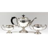 A George V silver circular three-piece tea service with C-scroll handles, on circular stepped