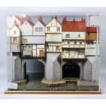 A painted wood cased model of the medieval London Bridge, showing timber framed buildings and a