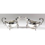 A pair of Elizabeth II silver oval sauce boats with shaped rims, leaf capped double C-scroll