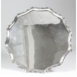 A George VI silver circular salver with shaped and moulded rim with bead mounts, on three scroll