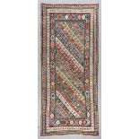 A Kazak Genje runner woven in colours with an angular striped centre field filled with stylised