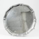 A George V silver circular salver with shaped and moulded rim, on three panelled feet, 10ins