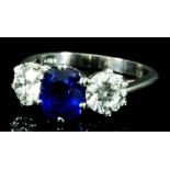 A modern 18ct white gold mounted sapphire and diamond three stone ring, set with central oval cut