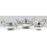 A George IV silver three-piece tea service, the squat circular bodies boldly embossed with flower