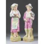 A pair of late 19th Century Continental bisque porcelain figures of a showman with magic lantern and