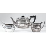 A George V silver oval three-piece tea service with reeded mounts and angular handles,