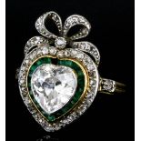 An 18ct gold and platinum mounted diamond and emerald ring of heart and ribbon pattern, set with
