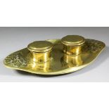 A German brass oval inkwell cast with oak leaves, and with two cylindrical inkwells, on panel