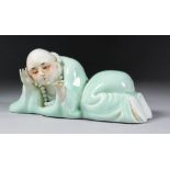 A 20th Century Chinese celadon glazed porcelain reclining figure by Fang Wangsheng, holding an