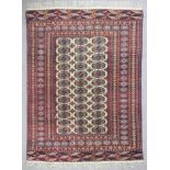 A Turkmen rug woven in navy blue, fawn and rose with three rows, each of twelve guls on a fawn