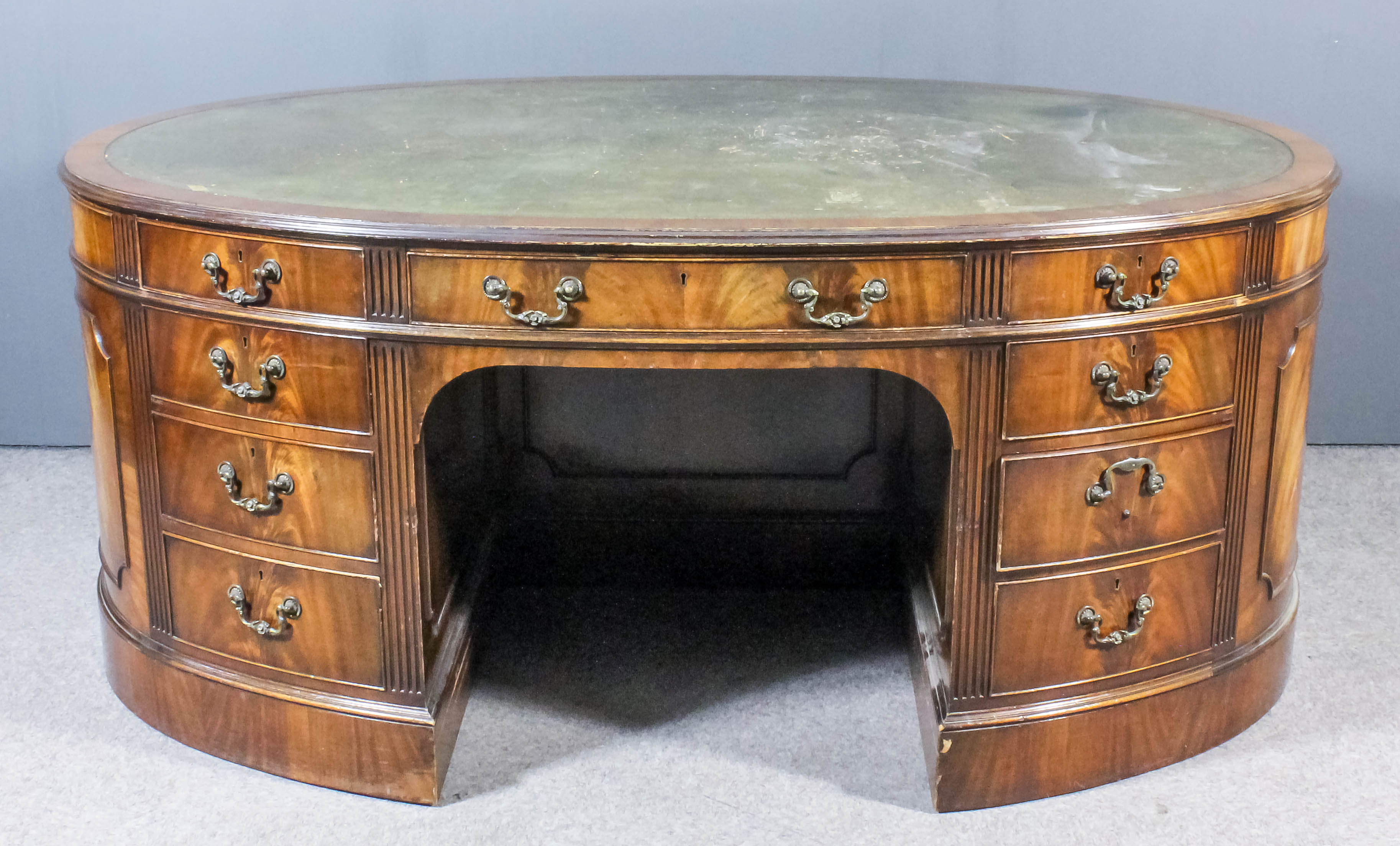 A mahogany oval kneehole partners desk of "Georgian" design with moulded edge to top and fluted