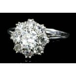 A platinum mounted and all diamond flowerhead pattern ring, set with central round brilliant cut