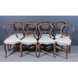 A set of six Victorian walnut balloon back dining chairs with moulded frames, fretted and scroll