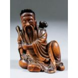 A Chinese carved and stained bamboo seated figure of a sage holding a sword and fly whisk, 3.