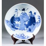 A Chinese blue and white porcelain circular dish, painted with prominent figures in a fenced garden,