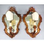 A pair of Italian gilt wood framed single branch wall lights with shaped and moulded back plates