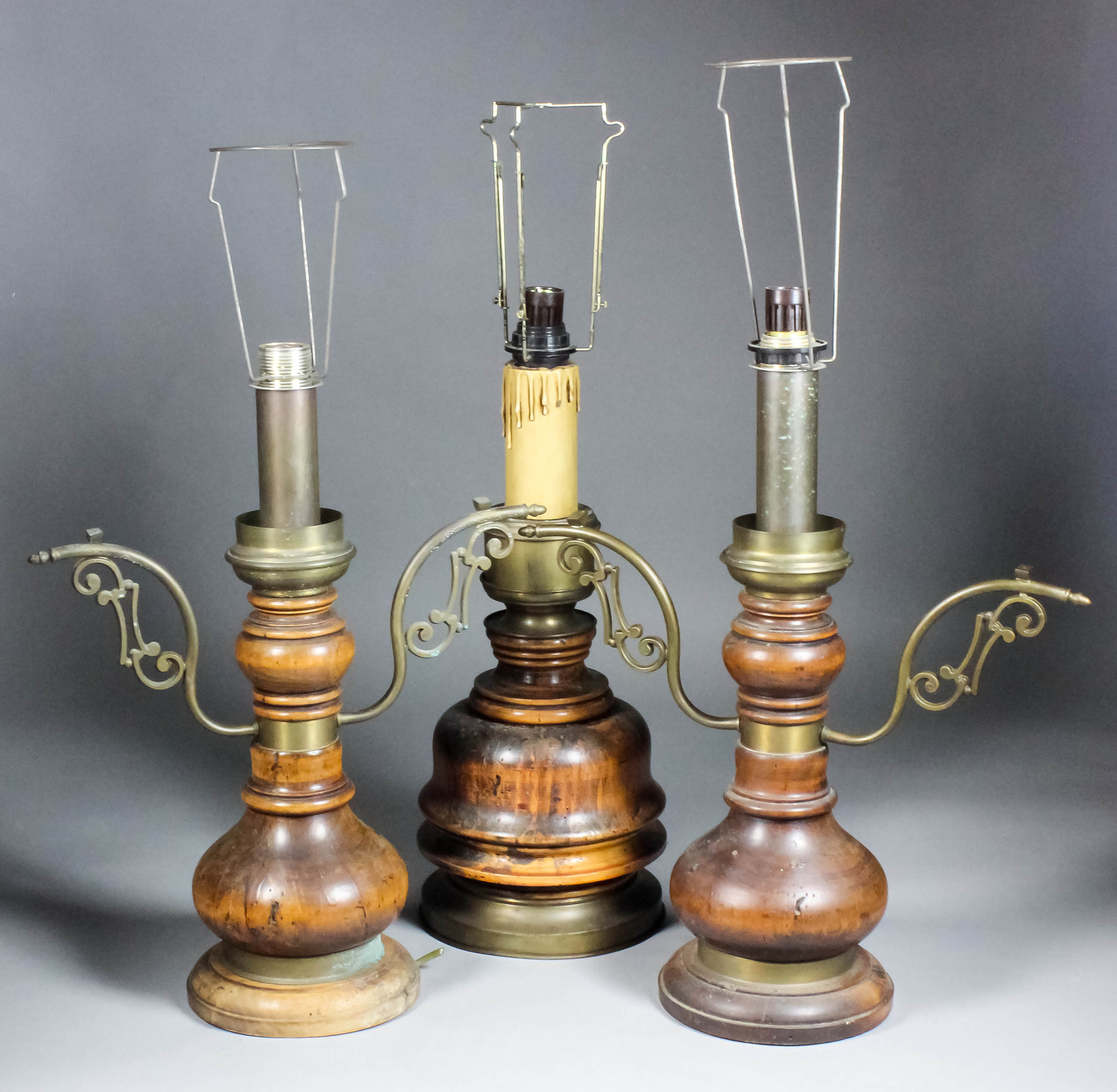 A pair of turned wood table lamps with brass arms, 19.5ins high, and another, 18.75ins high