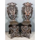 A pair of 19th Century Continental oak hall chairs, the high backs boldly fretted and carved with