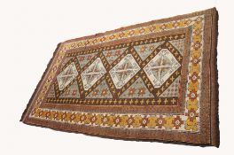 CAUCASIAN RUG, with a row of four diamond shaped medallions, pale green field decorated with brown