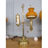 AN ADAPTED OIL LAMP WITH ORANGE GLASS GLOBE AND CLEAR GLASS FUNNEL