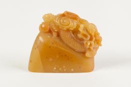 A CHINESE BROWN HARDSTONE SEAL of flattened section carved with a dragon, issuing from cloud