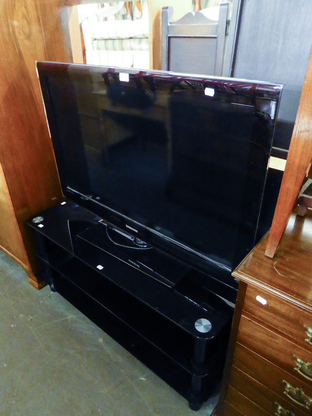 A SAMSUNG 40" FLAT SCREEN TELEVISION, ON BLACK GLASS THREE TIER STAND