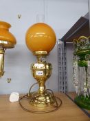 AN ADAPTED OIL LAMP WITH ORANGE GLASS GLOBE AND CLEAR GLASS FUNNEL