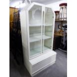 A MODERN WHITE DISPLAY CABINET, WITH INTERNAL LIGHT, OVER BASE HAVING ONE DRAWER