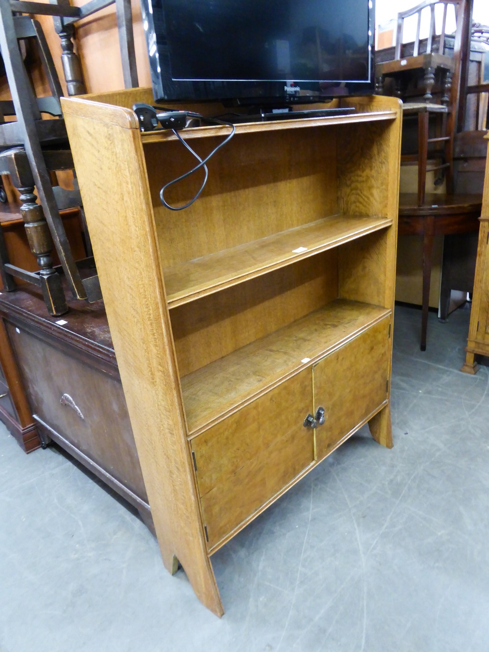 AN OAK OPEN BOOKCASE HAVING CUPBOARD BASE