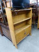 AN OAK OPEN BOOKCASE HAVING CUPBOARD BASE