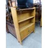 AN OAK OPEN BOOKCASE HAVING CUPBOARD BASE