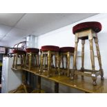 A SET OF EIGHT LOW BAR STOOLS, WITH RED FABRIC SEATS AND A MATCHING TALLER STOOL (9)