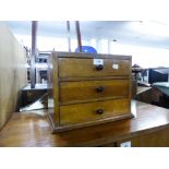 A TABLE TOP NEST OF THREE DRAWERS