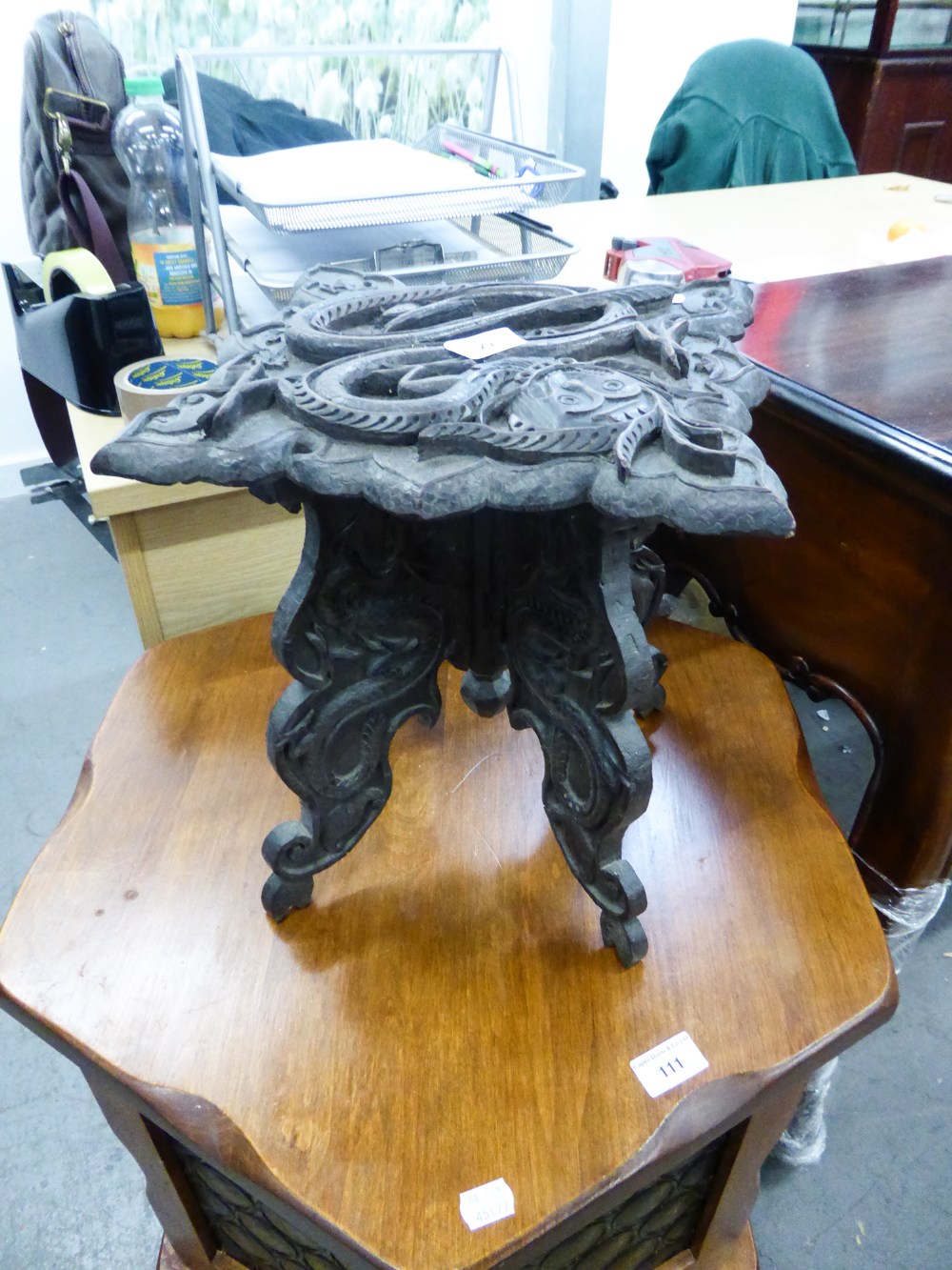 AN INDIAN HARDWOOD CARVED STOOL, THE SHAPED TOP WITH SNAKE AND BIRD DETAIL ON FOUR SHAPED SUPPORTS