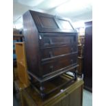 A VICTORIAN OAK PETITE BUREAU, FALL SLOPE FRONT OVER THREE GRADUATED DRAWERS, RAISED ON BALL