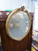 LATE NINETEENTH/ EARLY TWENTIETH CENTURY GILT GESSO OVAL WALL MIRROR, the bevel edged plate within a