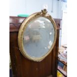 LATE NINETEENTH/ EARLY TWENTIETH CENTURY GILT GESSO OVAL WALL MIRROR, the bevel edged plate within a