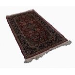 PERSIAN RUG, with midnight blue and floral lozenge shaped centre medallion on a red and Herati