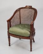 AN EDWARDIAN FLORAL PAINTED SATINWOOD CANE BACKED AND SEATED BERGERE ARMCHAIR (cane seat a.f.)