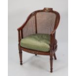 AN EDWARDIAN FLORAL PAINTED SATINWOOD CANE BACKED AND SEATED BERGERE ARMCHAIR (cane seat a.f.)