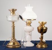 THREE EDWARDIAN OIL TABLE LAMPS, comprising: two in brass with etched glass shades, the other in