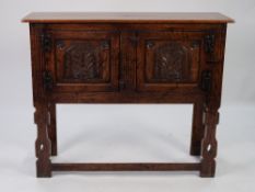 JACOBEAN STYLE CARVED AND DISTRESSED LIGHT OAK SIDE CABINET, the oblong top above a pair of panelled