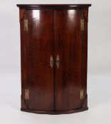 GEORGE III BOW FRONTED OAK CORNER CUPBOARD, of typical form with exposed brass H hinges, pierced