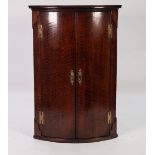 GEORGE III BOW FRONTED OAK CORNER CUPBOARD, of typical form with exposed brass H hinges, pierced