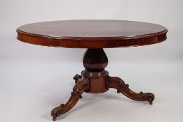 VICTORIAN CARVED AND FIGURED MAHOGANY LOO TABLE, the flame cut oval tilt top above a heavy base with