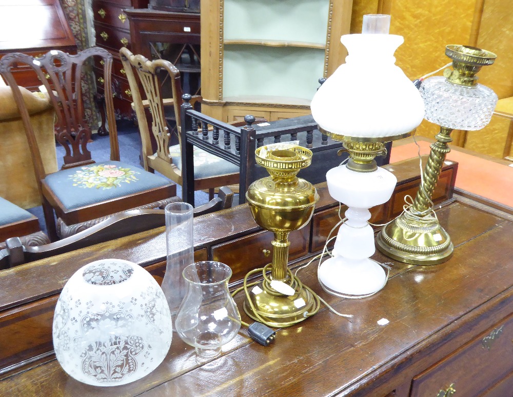 THREE EDWARDIAN OIL TABLE LAMPS, comprising: two in brass one with etched glass shade, the other